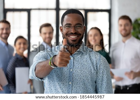 Best ever! Portrait of loyal excited black male client customer demonstrating thumb up sign recommending good product service, happy african employee looking at camera glad to work in company staff