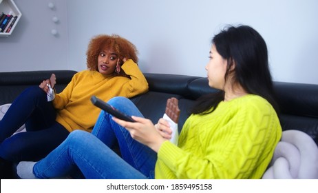 Best Friends Asian And African American Black Women Watching Tv And Eating Chocolate. . High Quality Photo