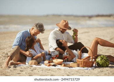 Best friends and couples celebrate Valentine's Day with a picnic on a sunny beach, enjoying food, wine, and laughter. Ideal for promoting romantic getaways, social gatherings, and beachside activities - Powered by Shutterstock