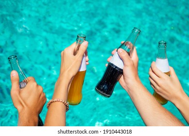best friends drinking lemonade while refreshing in the swimmingpool hands close up on blue aquamarine color background