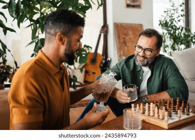 Best friends playing chess together, drinking whiskey and talking. Concept of male friendship, bromance. - Powered by Shutterstock