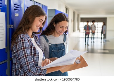 Best Friends Sharing Notes Standing Near Locker In College Campus. Happy Smiling University Students Laughing And Holding Notebook. Two Beautiful Girls Talking After Class At High School Hallway.