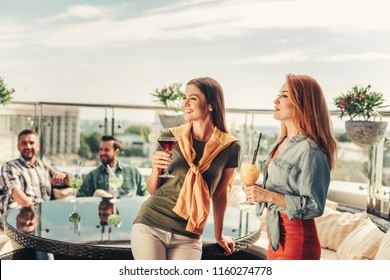 Best Friends. Smiling Lovely Women Enjoying Drinks At Rooftop Bar. Bearded Man Sitting At The Table With Mojito