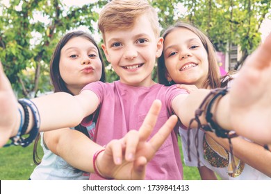 Best friends taking selfie outdoors in backyard – happy friendship with smart kids having fun celebrating summer vacation – modern children enjoying time together at garden party playing and smiling