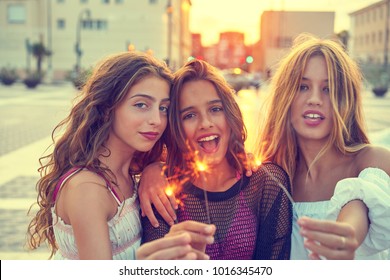 Best friends teen girls with sparklers at sunset in the city