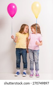 Best friends. Two cute little girls holding balloons on grey background.