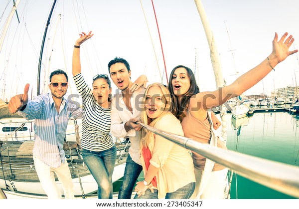 Best friends using selfie stick taking pic on exclusive luxury sailing boat party trip - Friendship travel concept with young people having fun together - Retro nostalgic desaturated color tone filter