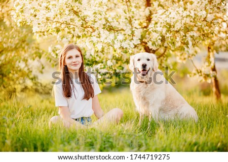 Best friends, young girl hugs labrador retriever dog and plays in park on summer day, sunlight.