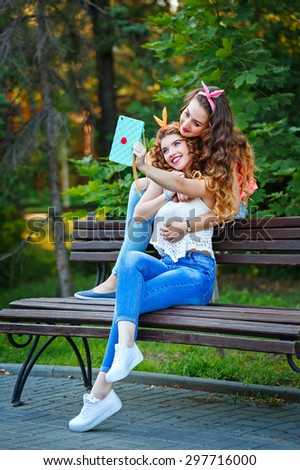 Best girlfriends hugging and making funny photos on the phone. Group selfies. Girls dressed in the style of Pin-up girl. Hipster. The concept of true friendship.
