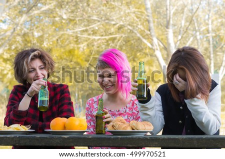 Best girlfriends laughing drinking beer - Three attractive young caucasian girls having fun outdoor.