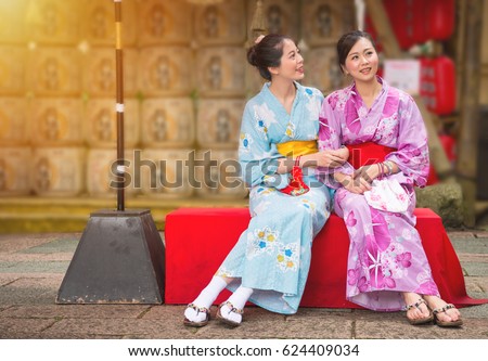 best girlfriends sitting on the culture street in Japanese festival with neat lantern background, women wearing japan traditional kimono enjoying art decoration during travel with copyspace.