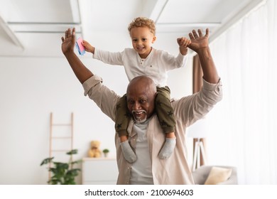 Best Grandfather. Cheerful Black Grandpa Carrying Little Grandson On Shoulders Playing And Having Fun Together At Home. Grandparent Spending Time With Happy Grandchild On Weekend