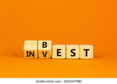 Best invest symbol. Turned wooden cubes and changed and changes the word 'invest' to 'best'. Beautiful orange background. Business and best invest concept. Copy space.