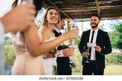 Best Man Performing Speech For Toast At Wedding Reception. Bride And Groom Listening To A Speech At Their Wedding Reception.