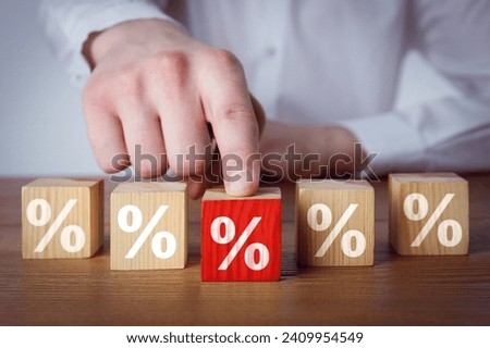 Best mortgage interest rate. Man pushing red cube with percent sign on wooden table, closeup