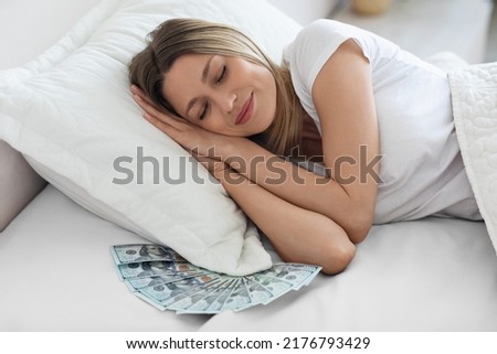 Best safe, money saving tips, finance management, financial health concept. Peaceful young woman sleeping alone and smiling, lot of cash under her pillow, closeup photo, bedroom interior