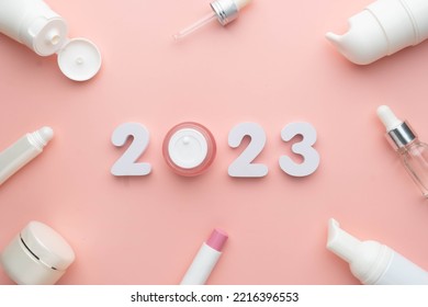Best skincare products and cosmetic trends of 2023 concept. 2023 white number with lip balm, cream bottle, serum and lotion on pink background. - Shutterstock ID 2216396553