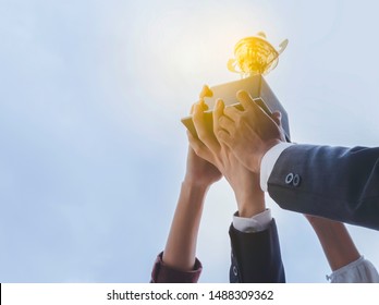 The Best Team Helped Each Other Reach Their Goals Target To Success. The Hand Of A Business Man And Business Women Pick Up The Trophy And Celebrate Together. Teamwork Of Successful Concept