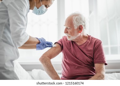 Best Treatment For You. Portrait Of Bearded Old Man Receiving Vaccine Shot In Hand While Sitting On Hospital Bed