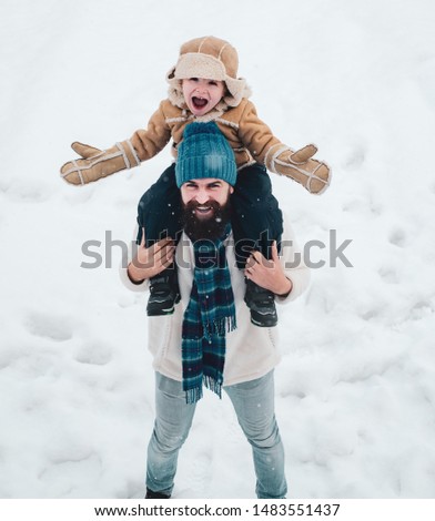 Best winter game for happy family. Father giving son ride on back in park. Family holiday and togetherness. Winter family in frosty winter Park