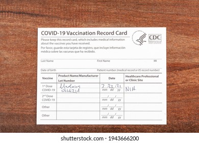 Bethesda, MD, USA 03-22-2021: A COVID 19 Vaccination Record Card On A Wooden Desk. The Card Details The Date, Type And The Dose Number Of Administred Vaccine And Given To Every Person For Record.