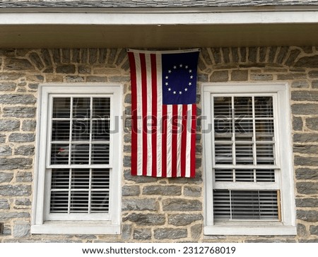 Betsy Ross 13 star American flag hanging from a historical stone building in Lititz, Pennsylvania during the day