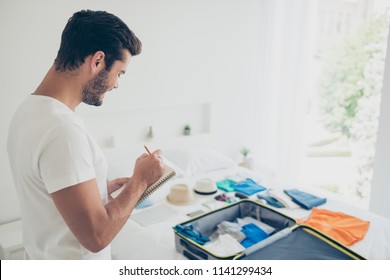 It's Better To Make A List! Joyful Brunet Man In A White T-shirt Writes Down What To Take With Him On A Trip