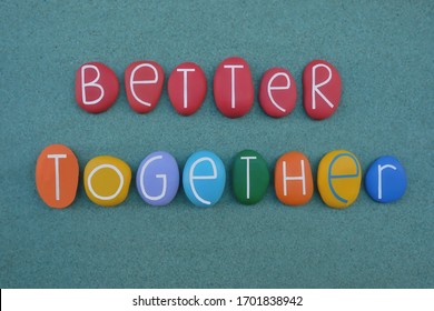 Better together, creative slogan composed with multi colored stone letters over green sand
