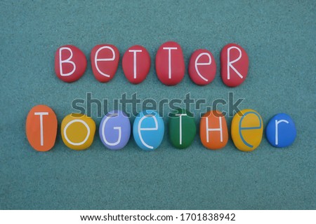 Better together, creative slogan composed with multi colored stone letters over green sand