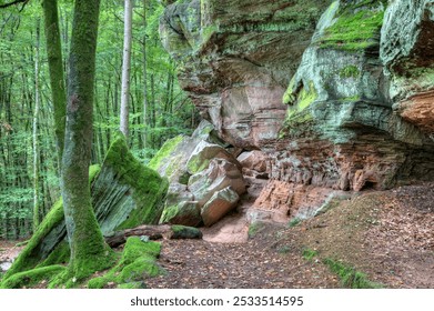 Between boulders and rock walls of colorful sandstone, the hiking trail winds through the Palatinate Forest, offering a path surrounded by nature's rugged beauty and ancient stone formations. - Powered by Shutterstock