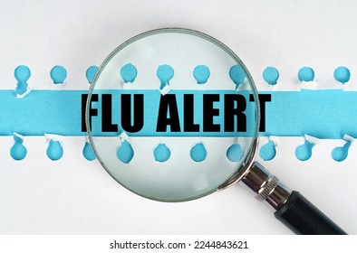 Between two sheets from a notebook on a blue stripe with the inscription - Flu alert, there is a magnifying glass. Medical concept.