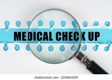 Between two sheets from a notebook on a blue stripe with the inscription - MEDICAL CHECK UP, there is a magnifying glass. Medical concept.