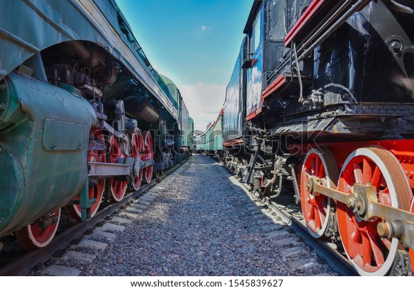 between wagons of old trains, between two old\
trains, red metal train\
wheels