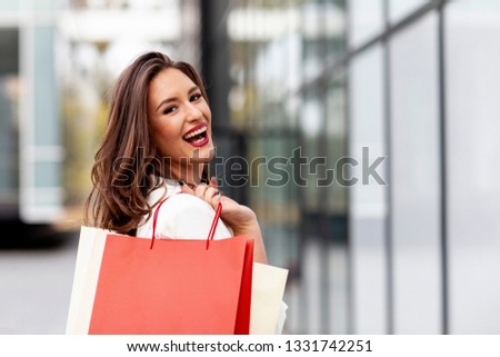 Beuatiful young long hair woman with shopping bags on her hands smile at the street