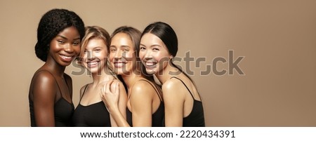 Beuaty portrait of Multi Ethnic Group of Womans with diffrent types of skin standing together and looking on camera. Diverse ethnicity women - Caucasian, African and Asian against beige background