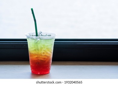 Beverage Juicy Soft Drink In Summer Concept. Freshness Mix Sweet Fruity Soda With Splash Ice In Plastic Glass With Straw On The Table Bar Over Natural Background.