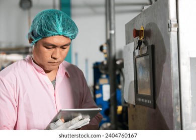 In beverage manufacturing a worker with a tablet supervises soda water filling while an engineer inspects machinery. Quality control ensures top-notch bottle production standards. - Powered by Shutterstock