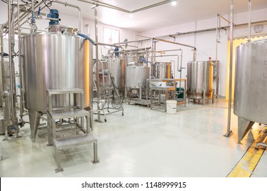 Beverage Production Line Background. A Liquid Mixer Tank Pumping Beverage Mix Into Bottle Filling Machine. Beverage Manufacturing Concept.