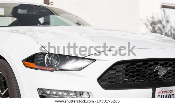 Beverly Hills, CA, USA 3-1-21: Front diagonal\
view of the exterior of the brand new 2021 Ford Mustang Coupe in\
white. Washington state license plate. Headlight, fog lamp, and car\
logo clearly visible.