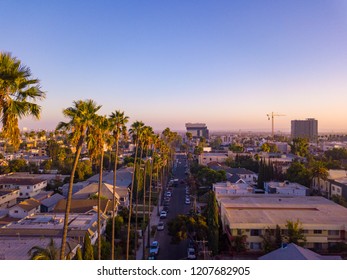 Beverly Hills Street With Palm Trees At Sunset In Los Angeles With Hollywood Sign On The Horizon.