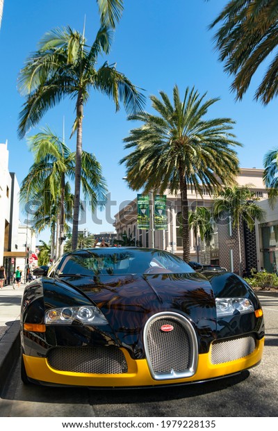 Beverly\
Hills. Year 2017: View of a famous Bugatti Veyron parked in Rodeo\
Drive. Black and yellow supercar. Expensive\
car.
