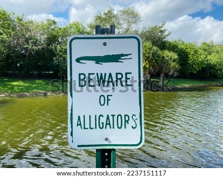 Beware of alligators warning sign next to Florida canal and lake