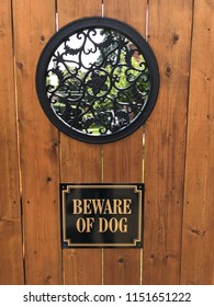 Beware Of Dog Sign On Brown Wooden Gate With Wrought Iron Window.