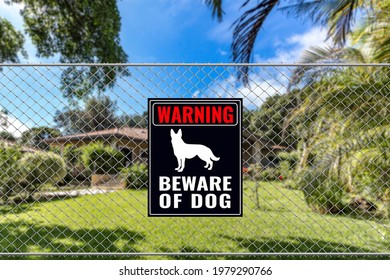 A Beware of Dog Sign on a fence near a bungalow house. Warning to visitors or burglars. Security and protection in a residential home concept.
