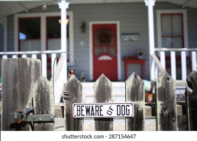 Beware Of Dog Sign For Security On Wooden Fence Outside Of Home Grey Ranch House With Red Door