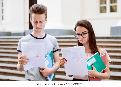 Bewildered and sad students holding papers with bad results of test