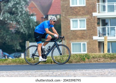 Bexhill-on-Sea, East Sussex, United Kingdom - September 5th 2021: A middle-aged male cyclist on the seafront at Bexhill-on-Sea riding a Fuji bike and wearing a blue jersey and a Kask helmet