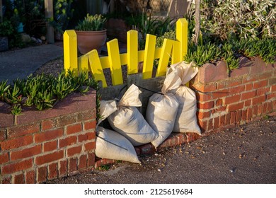 Bexhill-on-Sea, East Sussex, United Kingdom - February 18th 2022: Sandbags by a yellow front gate protecting a property on the promenade from flooding from a tidal storm surge after Storm Eunice