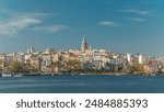 Beyoglu district historic architecture and Galata tower medieval landmark timelapse in Istanbul, Turkey. Many colorful houses reflected in water. Blue cloudy sky at spring sunny day