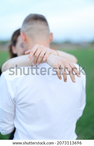 BFocus on ring, back view man hugging woman outside.